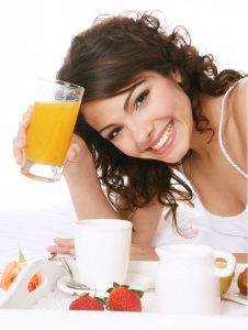 woman smiling with a glass of orange juice